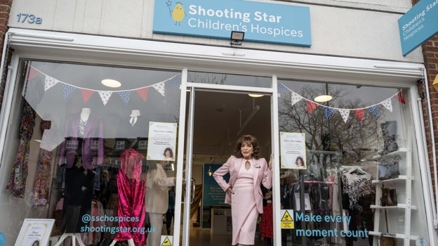 Collins posa en la fachada de la tienda de caridad ubicada en Hampton Hill