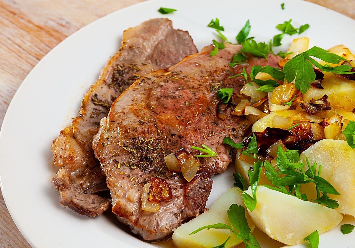 Chuletas de pavo acompañadas de patatas con tomate, orégano, cebolla y salsa tzatziki