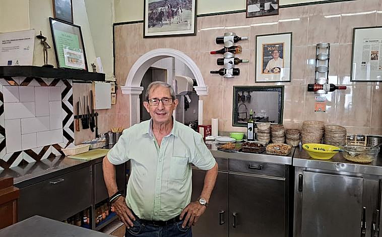 Imagen principal - Curro, detrás de la barra en la que ha estado 63 años; abajo, la fachada de la Bodega Consolación antes de cambiar de manos; y a la derecha, el cartel del homenaje que se le ha preparado este lunes en la Bodega Consola