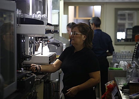 Imagen secundaria 1 - En la imagen superior, los responsables del Café Español tras la barra. Debajo a la izquierda, Marí Carmen Jiménez durante la preparación de los desayunos. A la derecha, atendiendo una mesa 