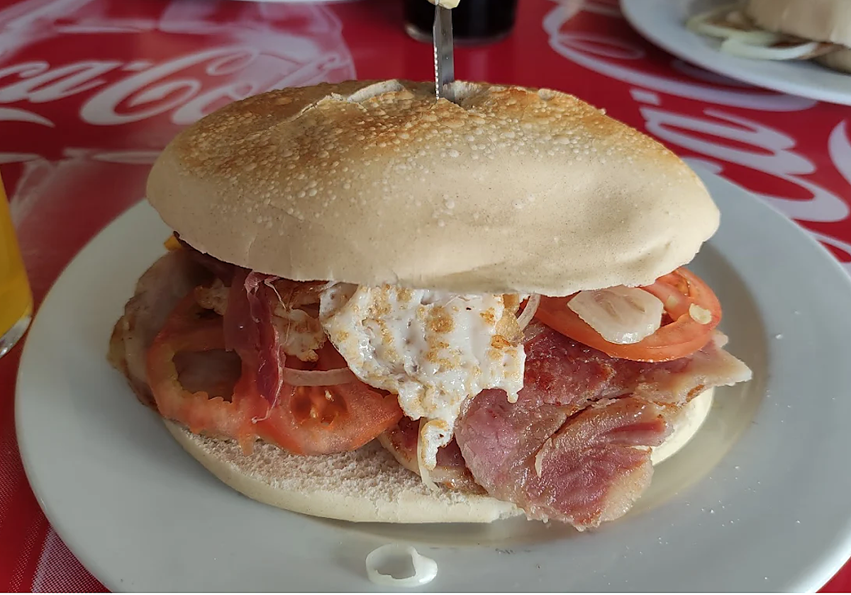 El 'Benjamín' es el bocadillo más famoso de este bar de Lebrija, un mollete de cochinito a la plancha, tomate, cebolla, huevo a la plancha. jamón y alioli verde