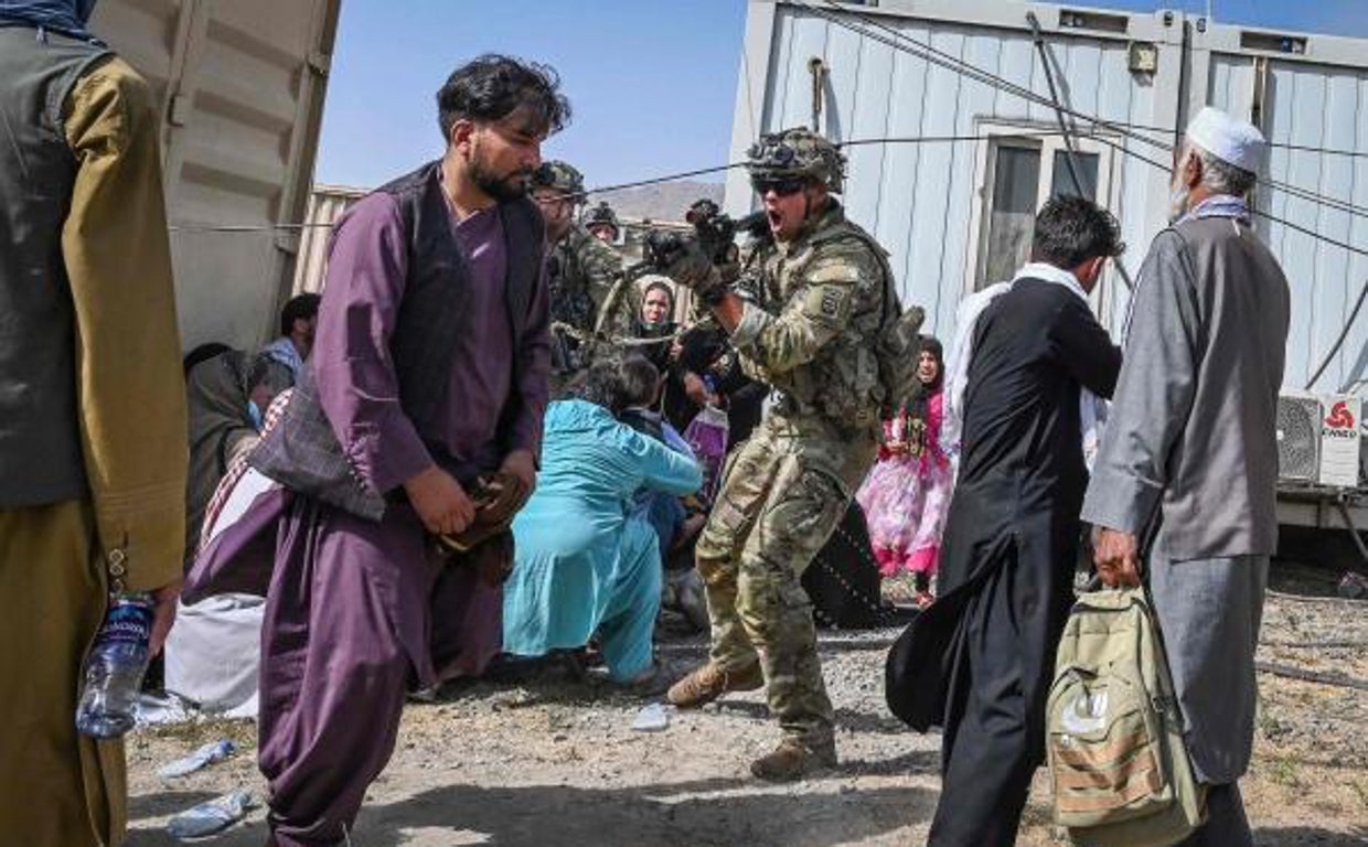Soldado estadounidense apuntando con su arma a un pasajero afgano en el aeropuerto de Kabul en Kabul el 16 de agosto de 2021