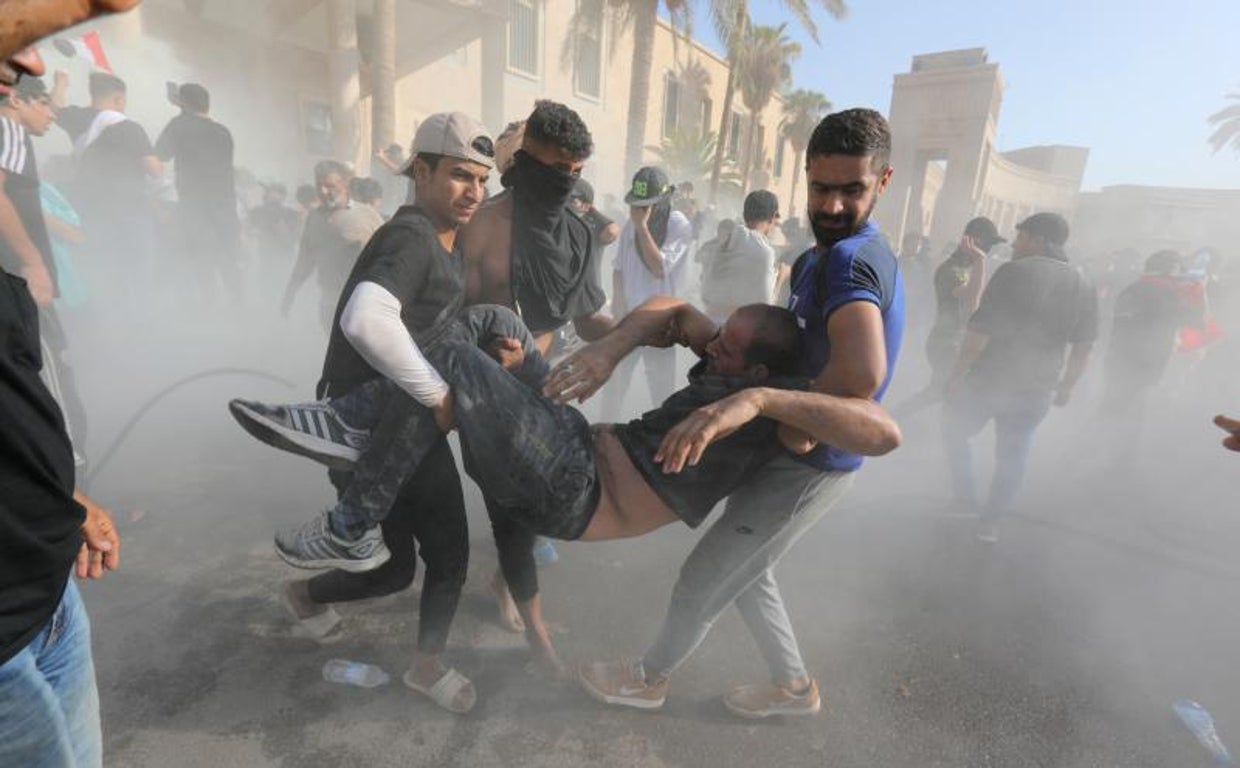 Los partidarios del clérigo chií iraquí Muqtada al-Sadr ayudan a los manifestantes heridos durante los enfrentamientos con las fuerzas antidisturbios cerca de la oficina del primer ministro