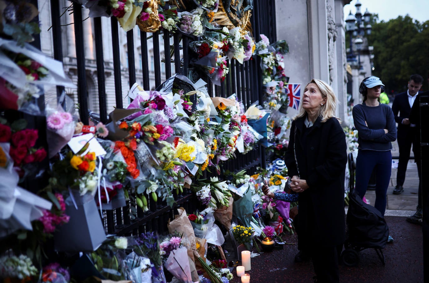 Una mujer observa los cientos de ramos de flores que se han depositado frente al Palacio