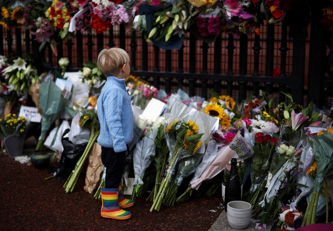 Un niño entre los ramos de flores que le han dejado a Isabel II
