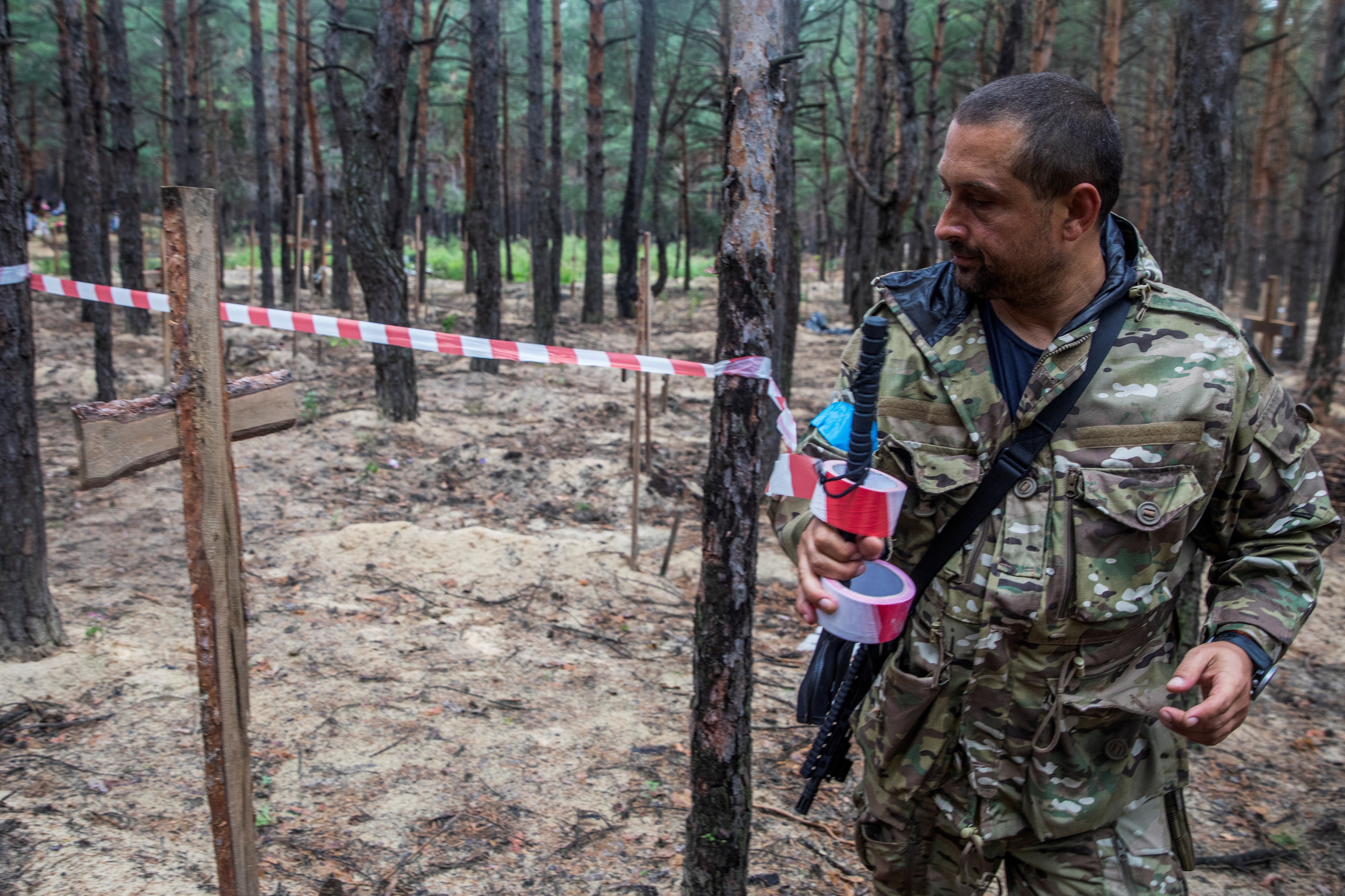 Un militar ucraniano acordona la zona donde van a ser exhumados los ucranianos fallecidos por la ofensiva
