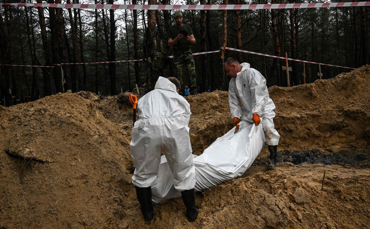 Los forenses sacan el cadáver de una fosa en Izium, hallada tras la retirada rusa