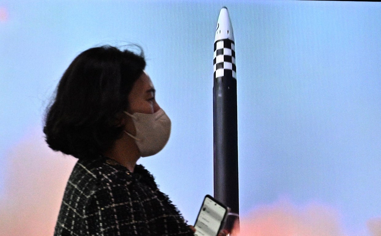 Una mujer pasa frente a la imagen deun misil norcoreano