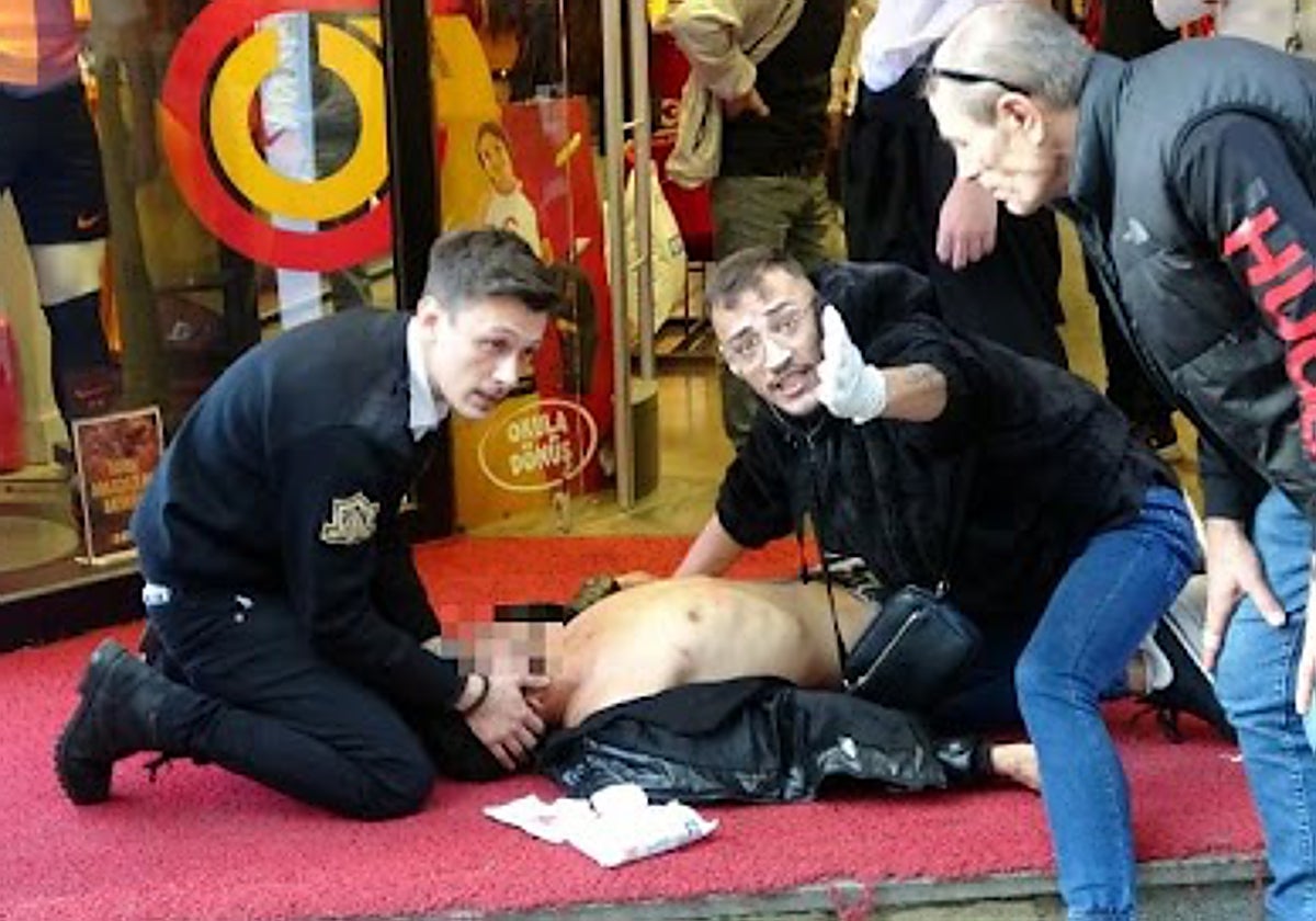 Varias personas de emergencias atendiendo a un herido en el lugar de la explosión