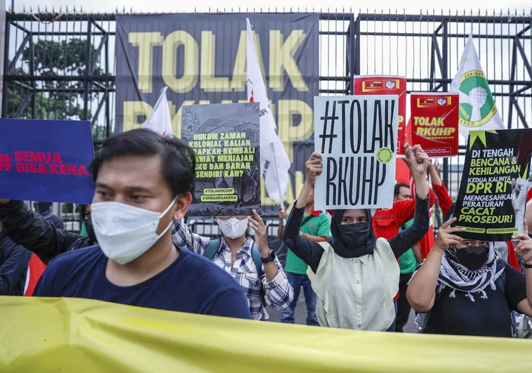 Los manifestantes sostienen pancartas que rechazan el proyecto de una nueva ley penal durante una protesta frente al edificio del parlamento en Yakarta, Indonesia