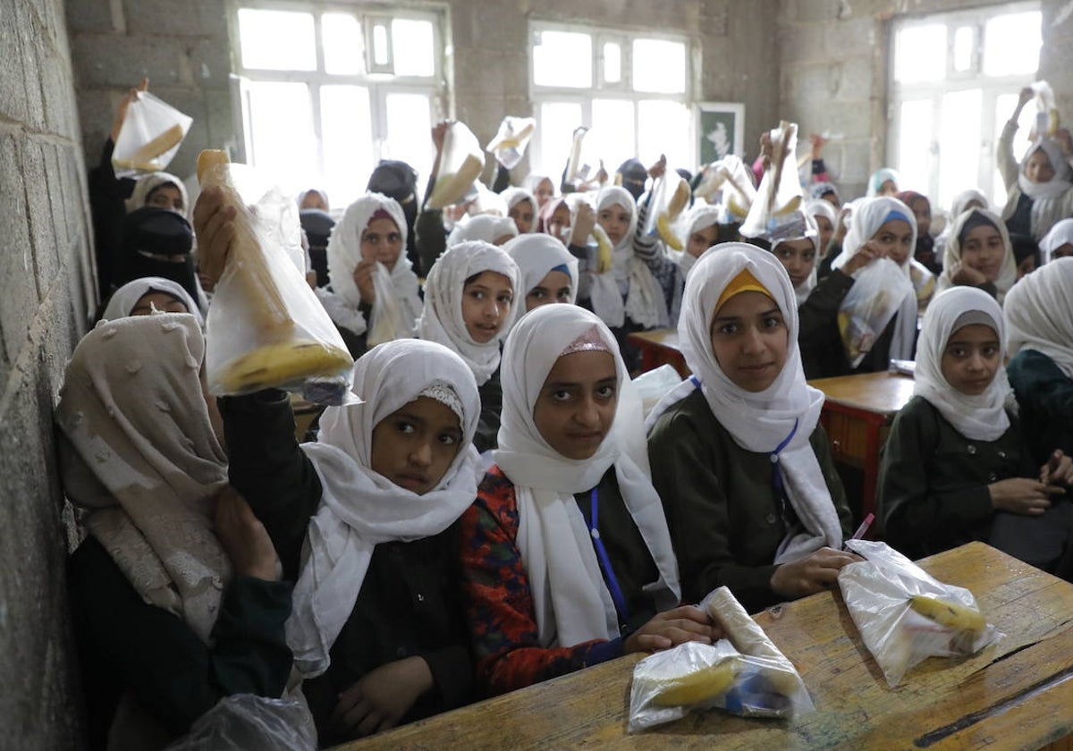 Niñas yemenitas muestran la bolsa del desayuno que les reparte la ONG