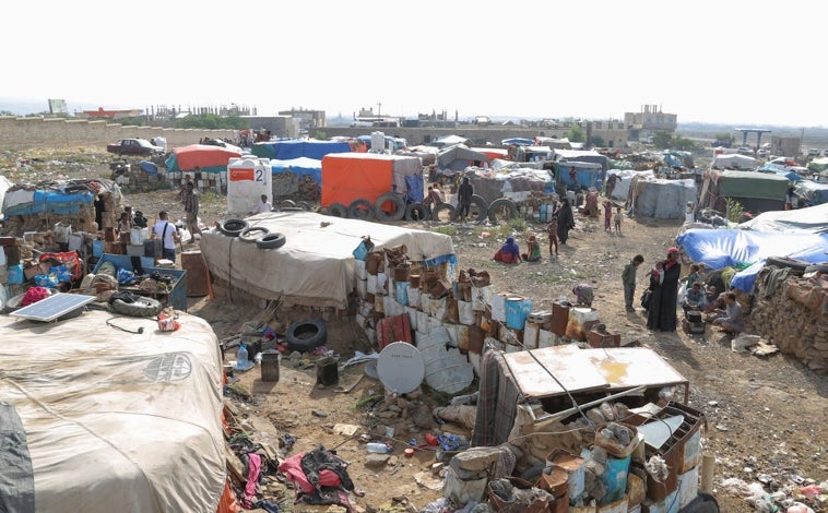 Imagen principal - Campamento de desplazados en Yemen, al que la ONG lleva depósitos de agua, el bien más escaso del país. Debajo, un grupo de niñas come su desayuno y otro niño del campo posa con los sacos de provisiones