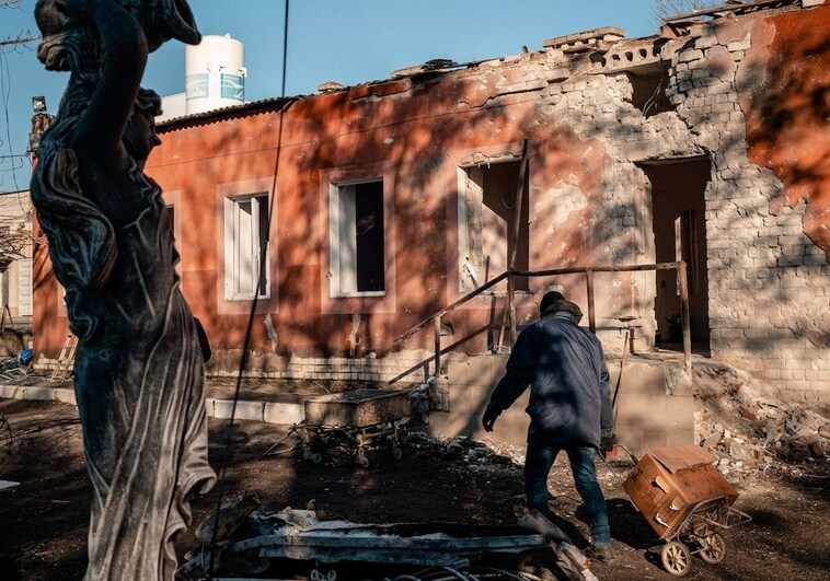 A man carries a cart in front of the bombed maternity ward in Kherson