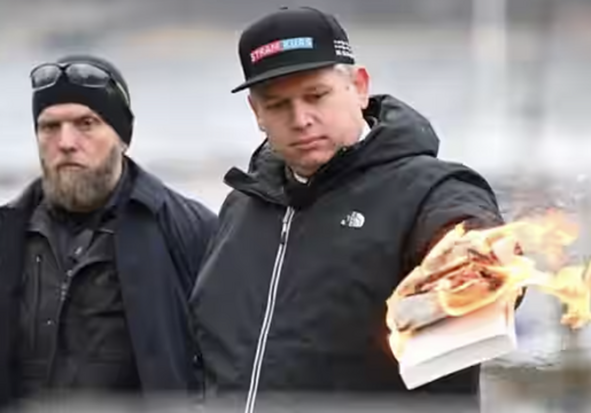 El líder del partido político danés de extrema derecha Stram Kurs, Rasmus Paludan, quema un ejemplar del Corán, mientras es vigilado por agentes de policía, mientras protesta ante la embajada turca en Estocolmo