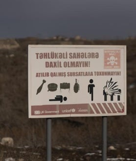 Imagen secundaria 2 - Arriba, imagen de las columnas de vehículos Rusos que discurren por la ruta entre Armenia y Karabaj. Debajo, a la izquierda, la protesta ecologista azerbaiyana que exige acceder a unos yacimientos cercanos y a la derecha, cartel en el territorio de Fizuli, al este de Karabaj, que alerta de la existencia de minas antipersona