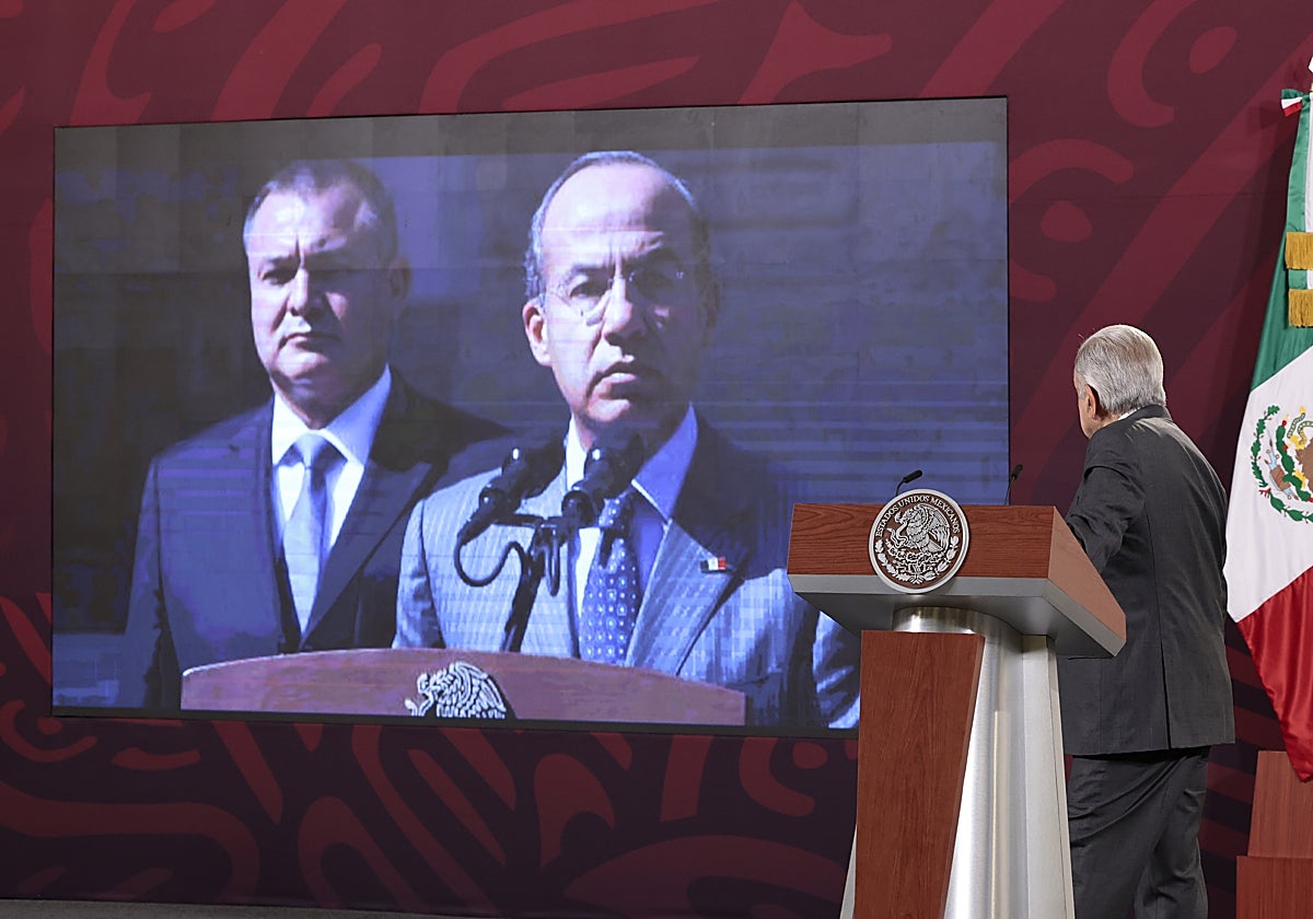 El presidente Andrés Manuel López Obrador, esta semana, mira una imagen de García Luna (al fondo) con Felipe Calderón