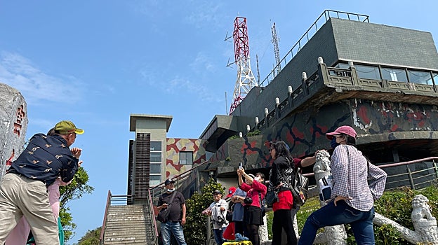 Turistas taiwaneses se hacen una foto bajo el edificio de inteligencia militar del monte Yuntai, un puesto de observación desde el que se vigila la cercana costa de China