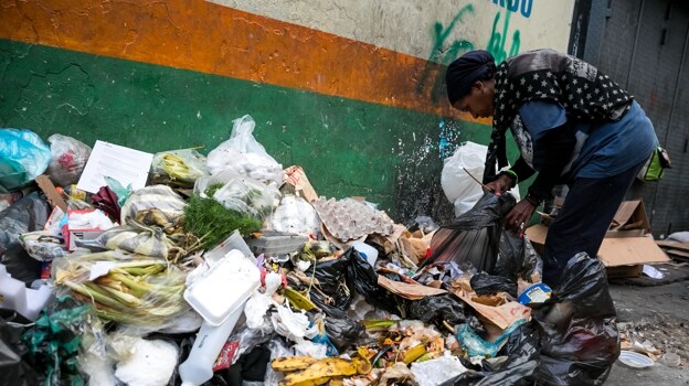 Una mujer mientras hurga en una basura en busca de comida en una calle de Caracas, in 2017
