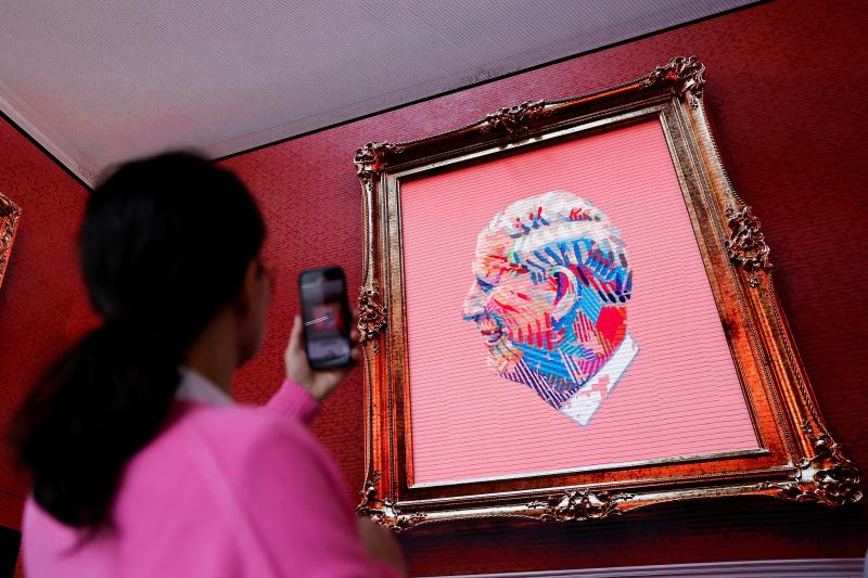 Una persona graba imágenes de una proyección de la obra de arte 'The Royally Big Portrait', un retrato digital  del rey Carlos que presenta miles de retratos individuales suyos dibujados por niños de todo el Reino Unido