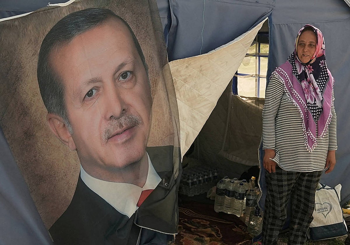 Ayse Kekec, una sobreviviente del terremoto que vive en una tienda de campaña con su hijo, frente a su tienda con un cartel del presidente turco Erdogan