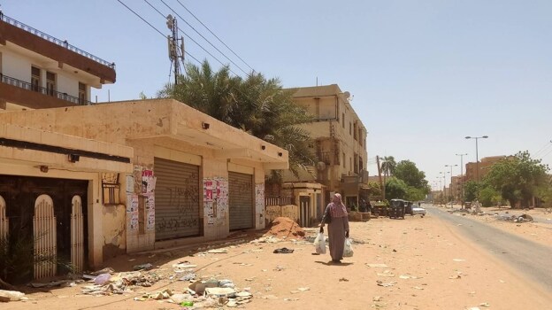 Una mujer camina por una calle en Jartum el 18 de mayo de 2023, mientras continúa la violencia entre los generales sudaneses