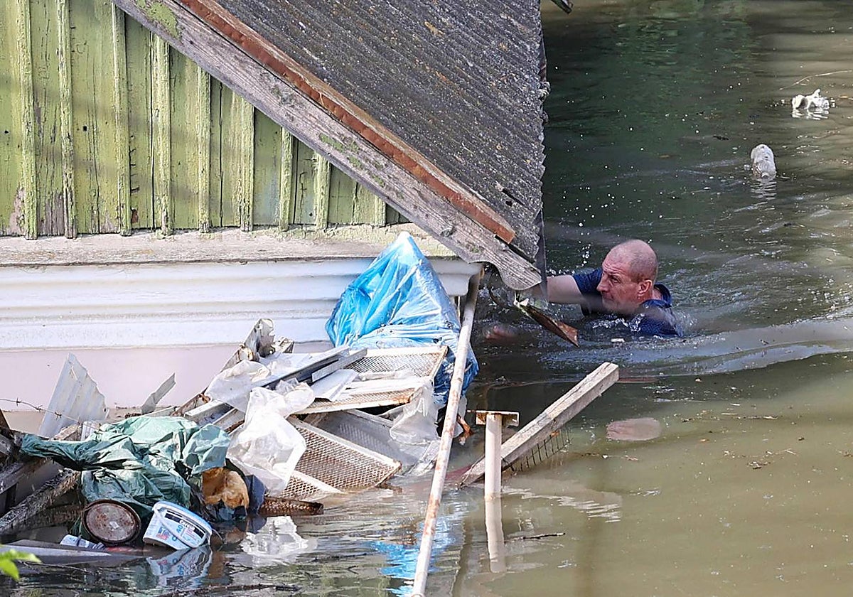 Un residente local nada junto a una casa en un área inundada en Jersón el 7 de junio de 2023, luego de la destrucción de la represa de la central hidroeléctrica Kakhovka