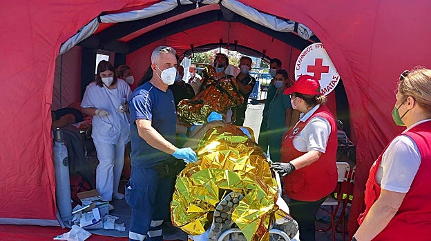 Paramédicos del Servicio Nacional de Ambulancias de Emergencia (EKAV) de Grecia y miembros de la Cruz Roja Griega ayudan a los migrantes a su llegada al puerto de Kalamata,