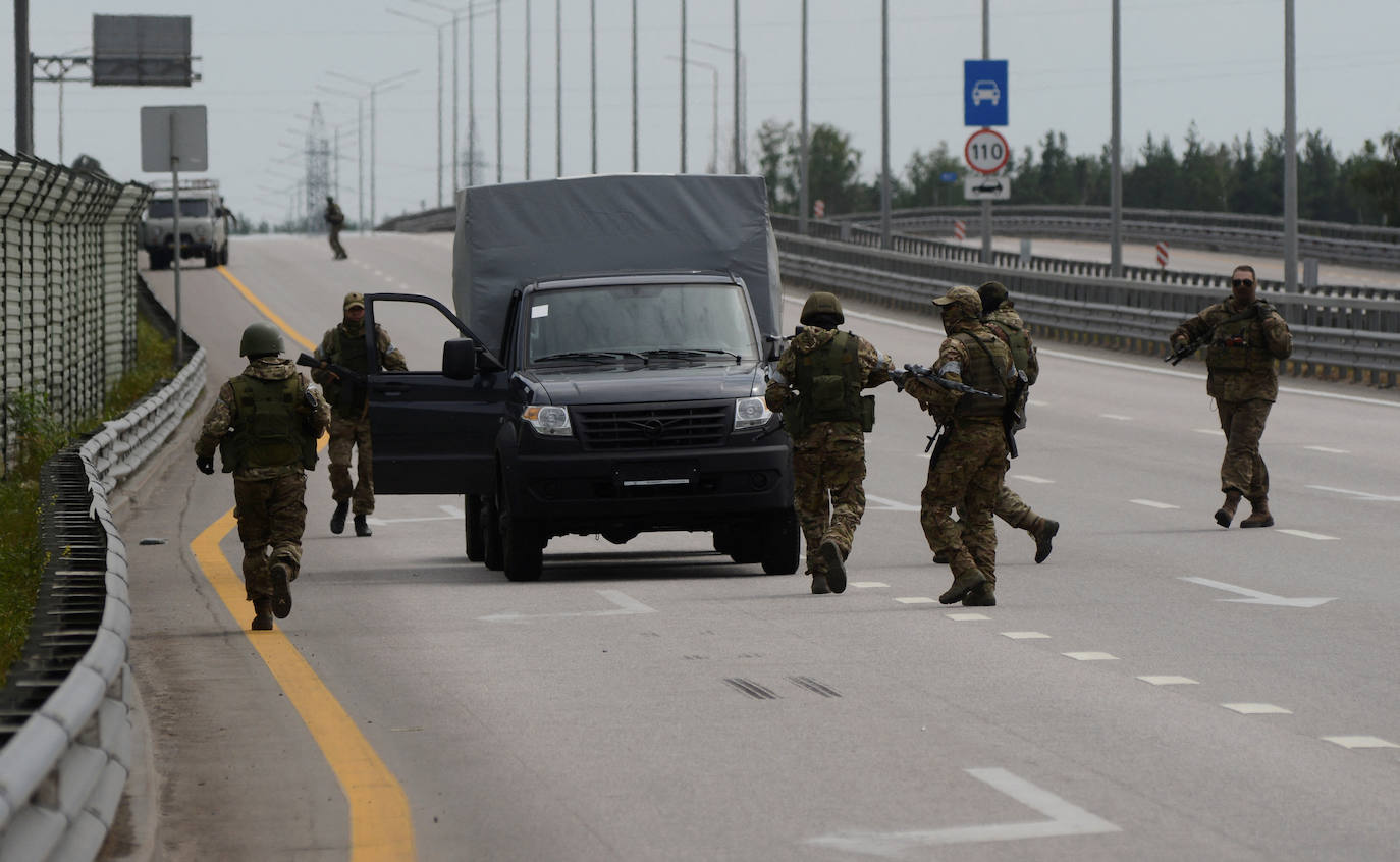 El grupo de mercenarios privados de Wagner caminan alrededor de un vehículo durante una parada en la autopista M-4, que une la capital Moscú con las ciudades del sur de Rusia