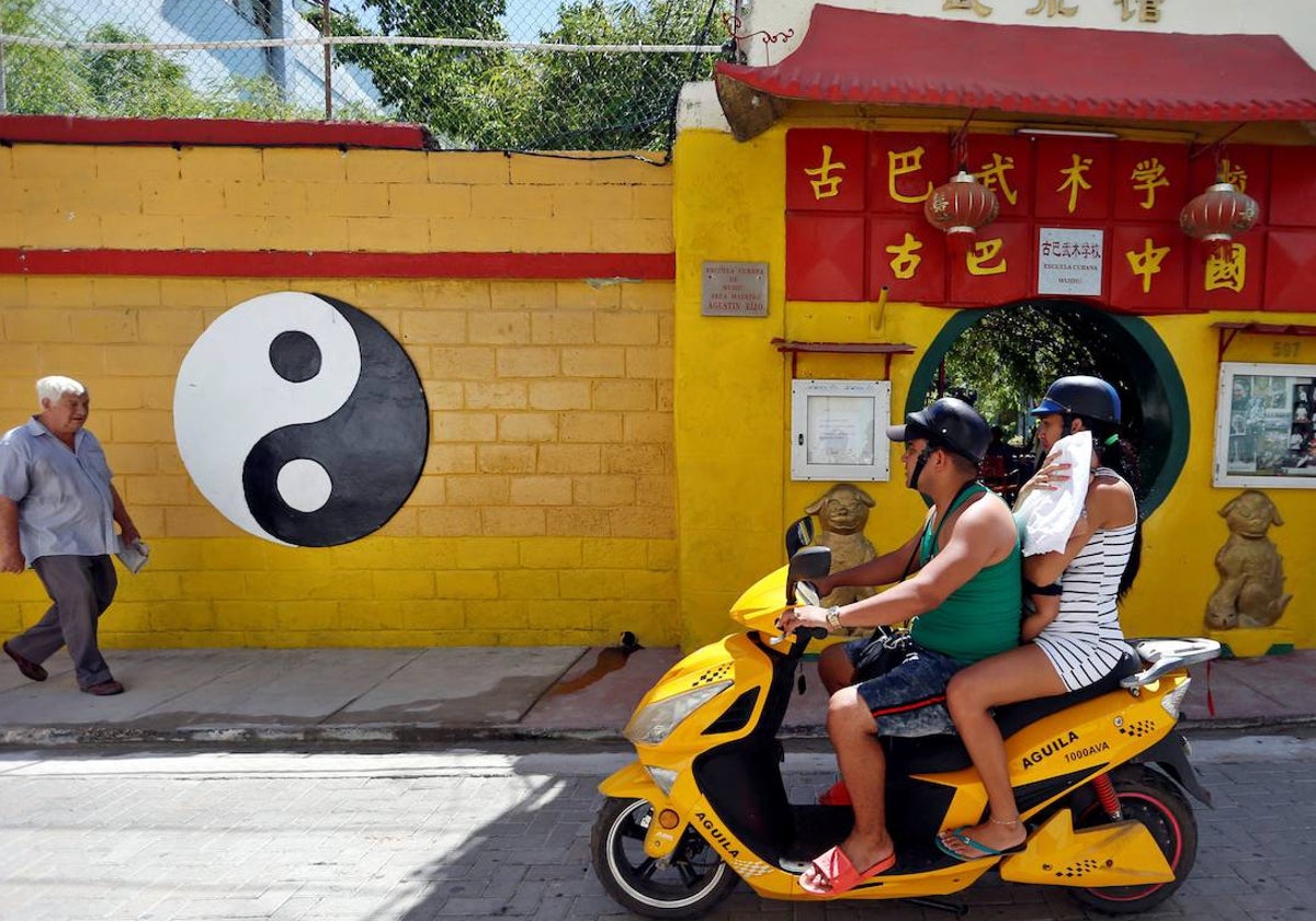 Un hombre pasea y una pareja sube en moto por el barrio chino de la Habana