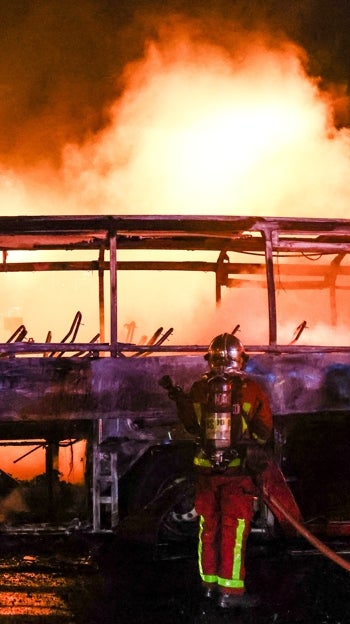 Los bomberos apagan un autobús durante los enfrentamientos entre manifestantes y la policía antidisturbios en Nanterre