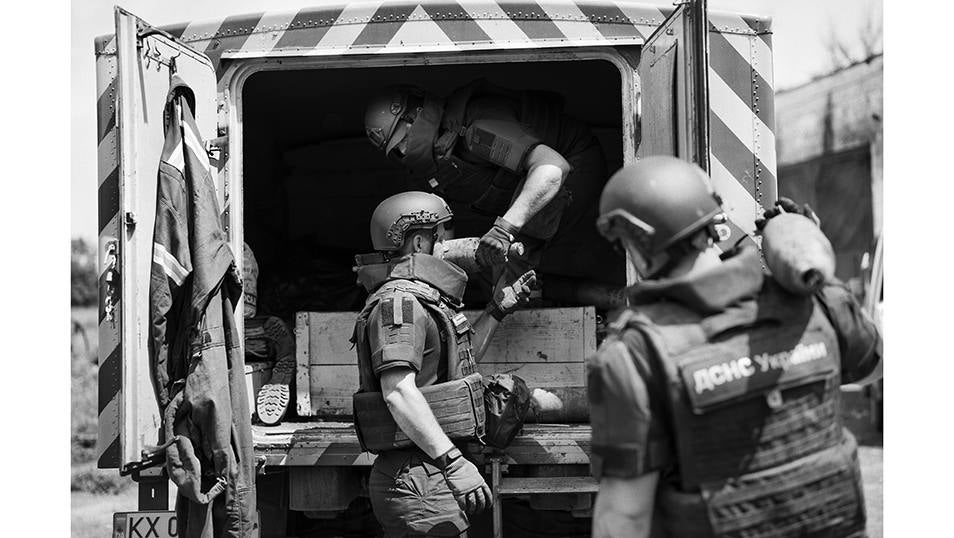 Miembros de una unidad de desminado de los servicios de emergencia de Ucrania trasladan obuses sin explotar de una antigua posición militar rusa a un camión blindado de su unidad.