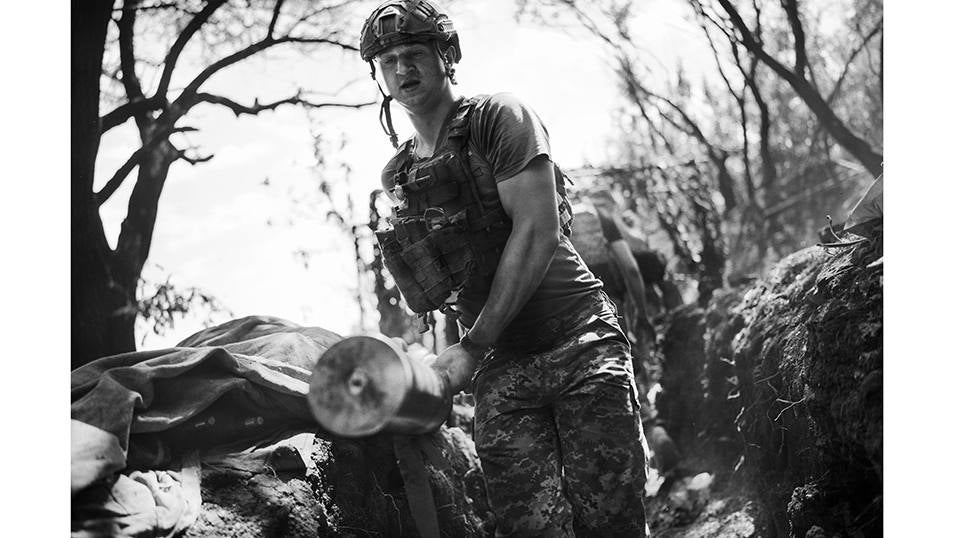 Un solado de la Brigada 80 retira la vaina de un proyectil incandescente recién disparado en la linea del frente de Bakhmut