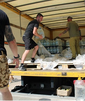 Imagen secundaria 2 - Serhiy camina entre sus viñedos (IZQ). Reparto de bidones de agua en Nikopol (DRCH.) Vecina lleva varias garrafas de agua (Arriba)