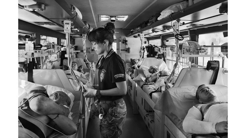 Donestk, Ucrania - Julio 06, 2023: Una doctora del equipo médico de la unidad de evacuación del autobús hospitalizado atiende a un soldado herido ucraniano herido en frente de Pisky