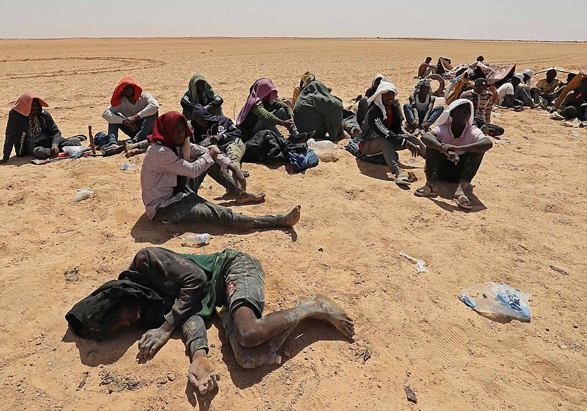 Un grupo de inmigrantes expulsados por Túnez a Libia intenta protegerse del sol en el desierto