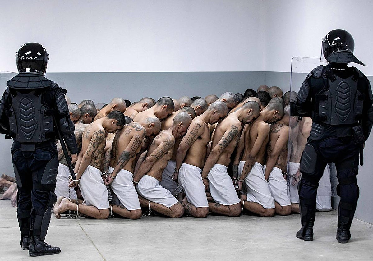 Dos policías salvadoreños vigilan a una fila de pandilleros detenidos