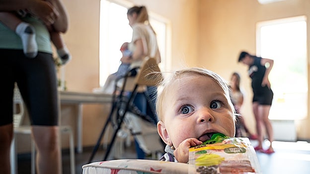 Darynka, jugando en el comedor del refugio; al fondo, algunas de las madres y niños que viven en él