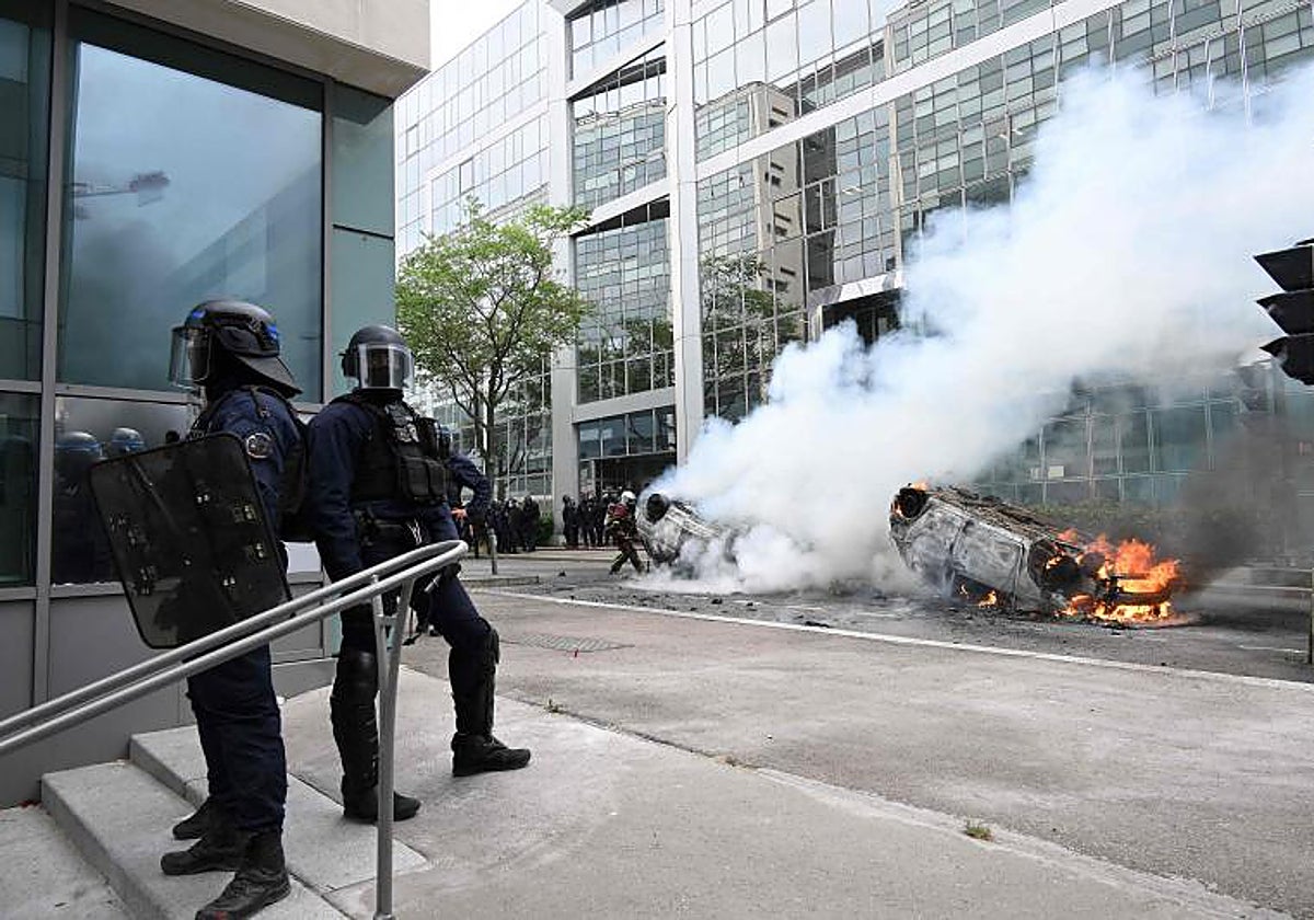 Policías con equipo antidisturbios se paran junto a autos que arden en la calle al final de una marcha de conmemoración de un conductor adolescente asesinado a tiros por un policía, en el suburbio parisino de Nanterre.
