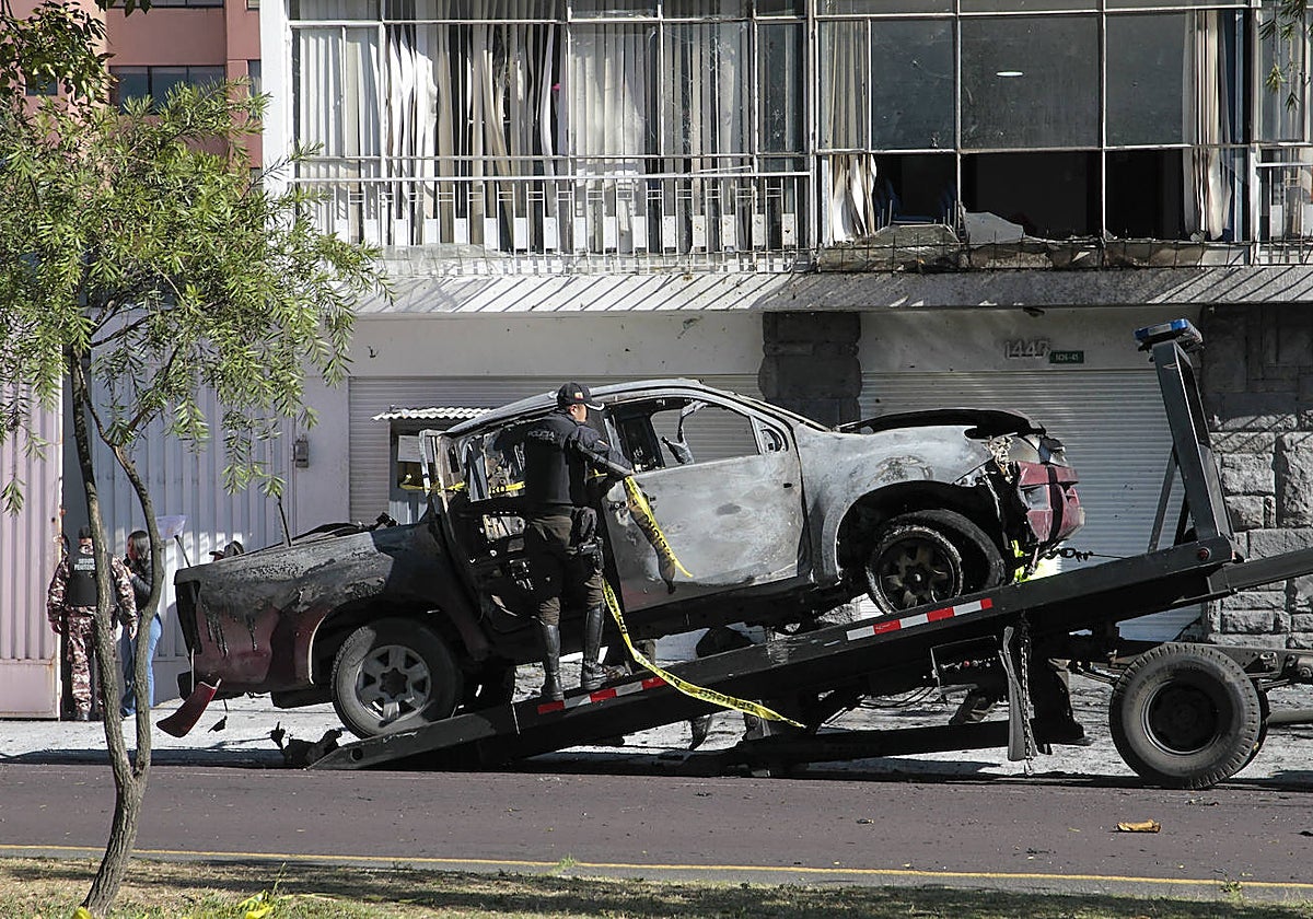 Un policía carga en una grúa los restos de un carro bomba que explotó en la madrugada en los exteriores del edificio del Servicio Nacional de Atención Integral a Personas Privadas de Libertad (SNAI), en Quito