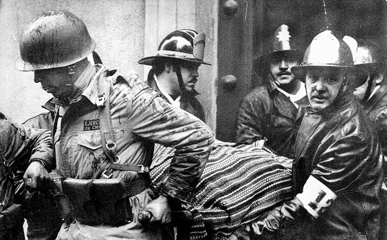 Imagen principal - Soldados y bomberos cargan el cuerpo del presidente Salvador Allende, envuelto en un poncho boliviano, fuera del destruido palacio presidencial de La Moneda después del golpe encabezado por el general Augusto Pinochet que puso fin al gobierno de tres años de Allende