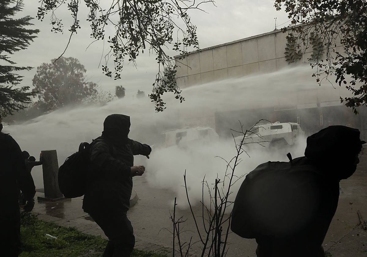 Encapuchados se enfrentan con policías durante una manifestación por los 50 años del golpe de Estado contra el Gobierno democrático de Salvador Allende, este domingo, en inmediaciones del Palacio de la Moneda