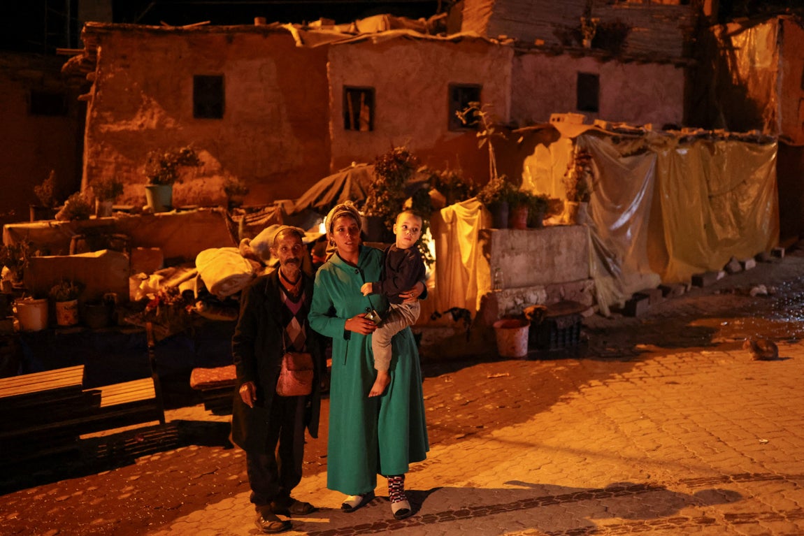Una familia y de fondo su vivienda dañada a causa del terremoto