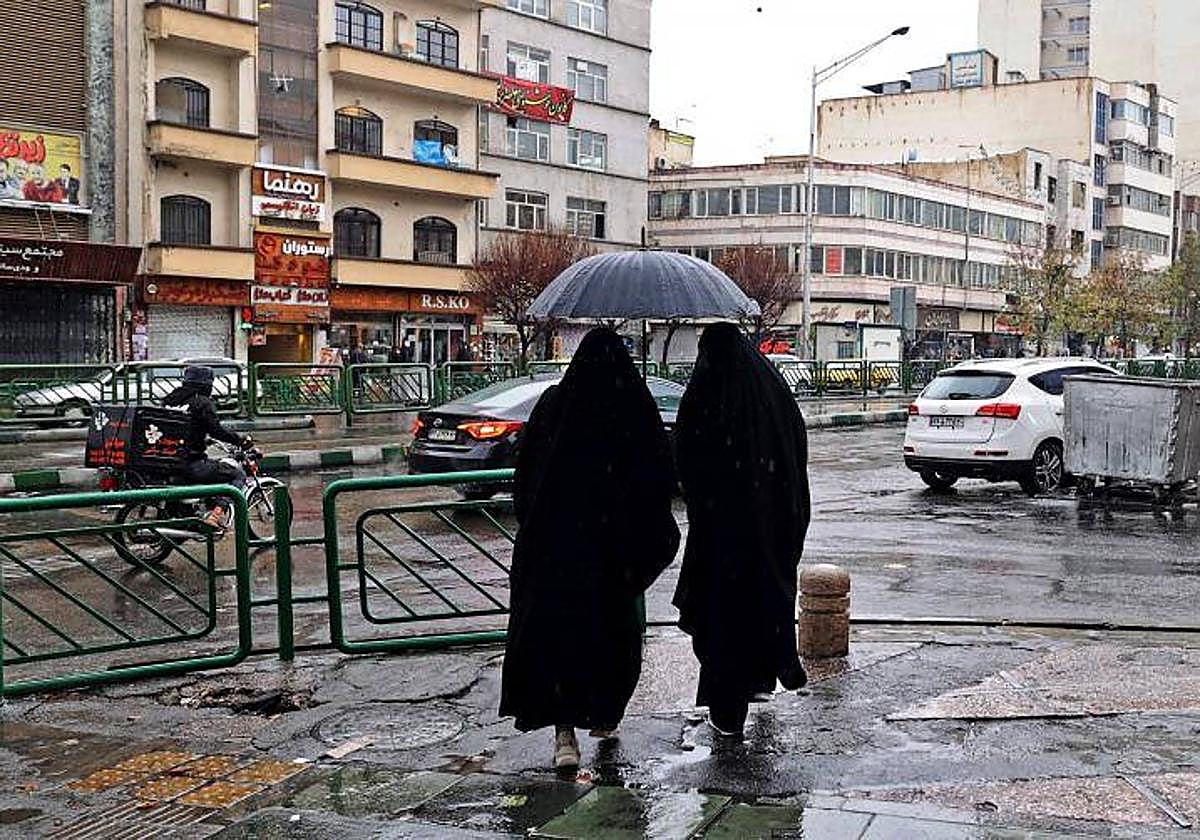 Dos mujeres con chador caminan por la plaza Enghelab, en Teherán