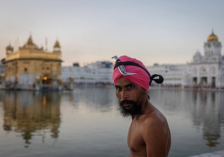 Un devoto sij se prepara para darse un chapuzón en el Sarovar, o estanque sagrado, en el sagrado santuario sij del Templo Dorado de Amritsar.