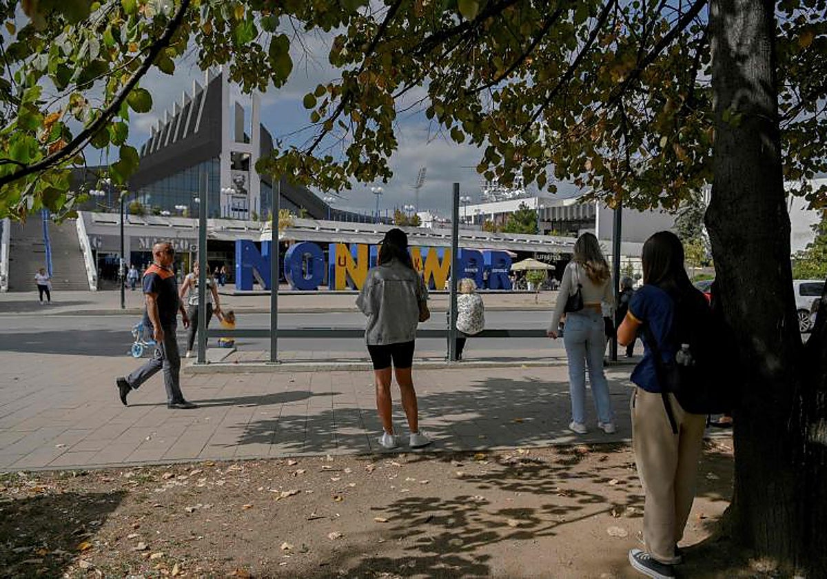 La gente espera un autobús frente al monumento a la independencia de Kosovo 'Newborn' convertido en 'No New Broken Republic' en Pristina