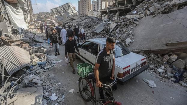 Palestinos pasan por las ruinas de edificios destruidos en Khan Yunis