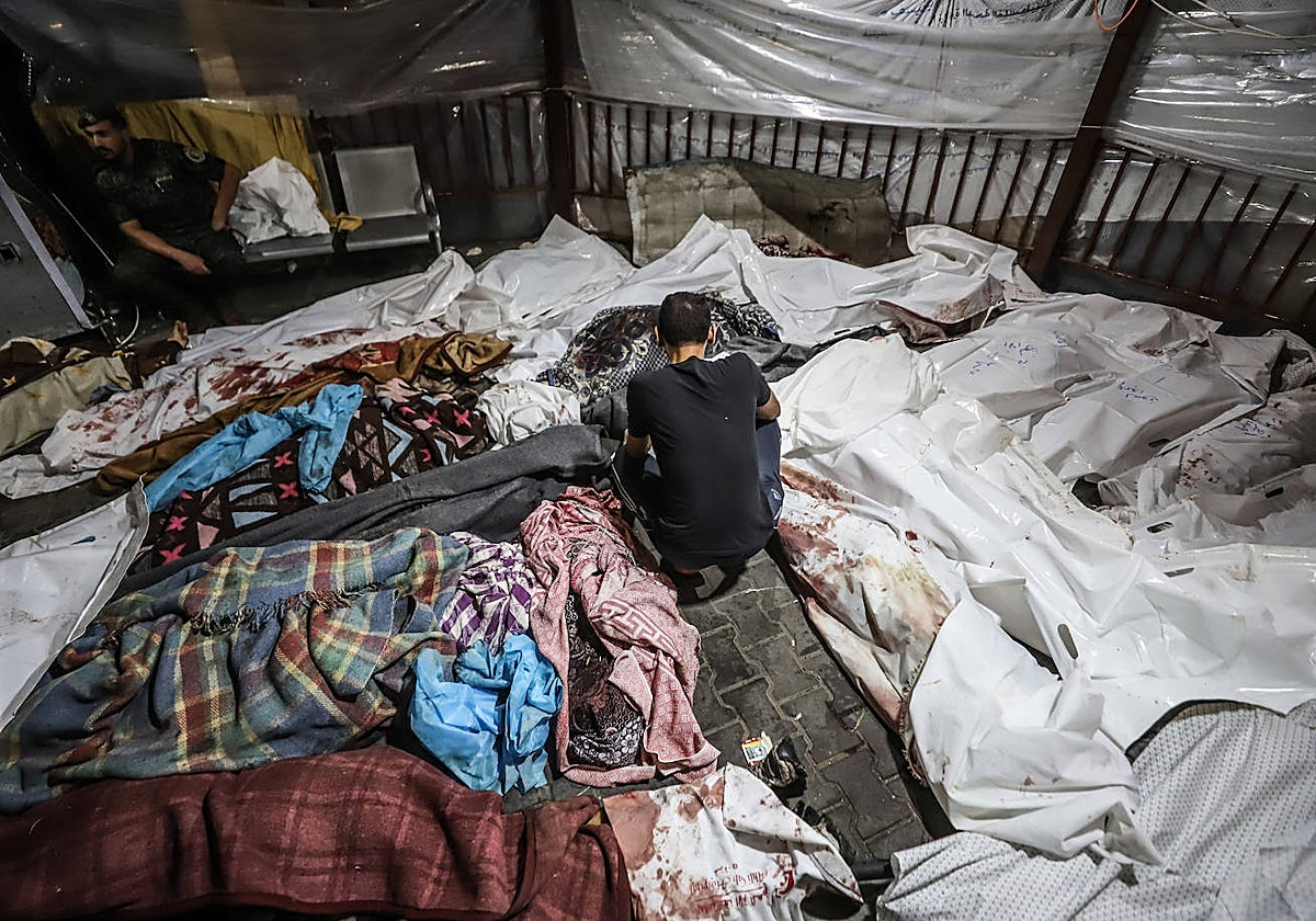 Cadáveres de varios palestinos muertos en un bombardeo contra el hospital Ahli Arab yacen en el hospital Al Shifa de Gaza