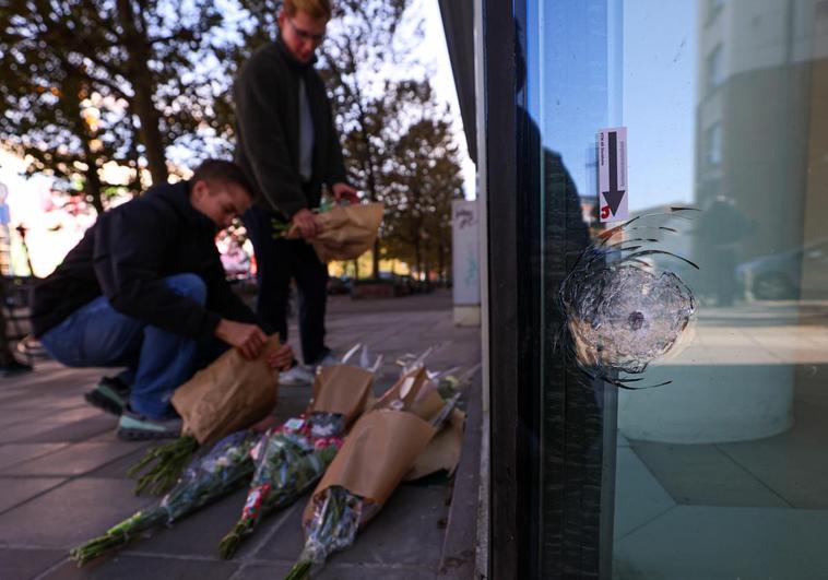 Un grupo de personas deposita flores en la sucursal bancaria en la que dos hinchas de fútbol suecos murieron tiroteados en un atentado terrorista en Bruselas