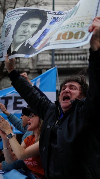 El candidato presidencial Javier Milei sostiene una pancarta con su rostro en un billete de dólar