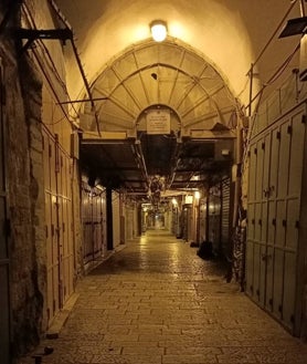 Imagen secundaria 2 - En la foto superior, la Ciudad Vieja de Jerusalén, cerca de la Puerta de Jaffa. Debajo, el río Jordán como frontera: a la izquierda, Israel; a la derecha, Jordania, en el sitio del bautismo de Jesús. Por último, el zoco de Jerusalén con los comercios cerrados, sin turistas